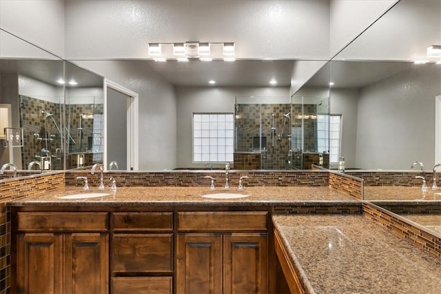 full bathroom with double vanity, a stall shower, a sink, and a wealth of natural light