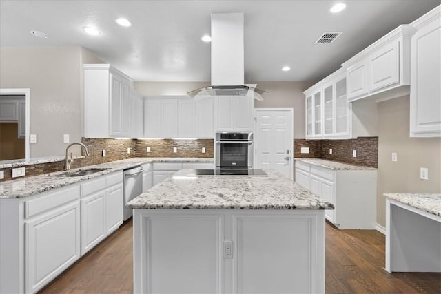 kitchen with black electric stovetop, a sink, visible vents, ventilation hood, and stainless steel dishwasher