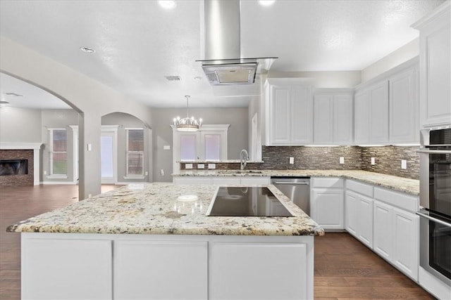 kitchen featuring a center island, stainless steel appliances, backsplash, white cabinetry, and a sink