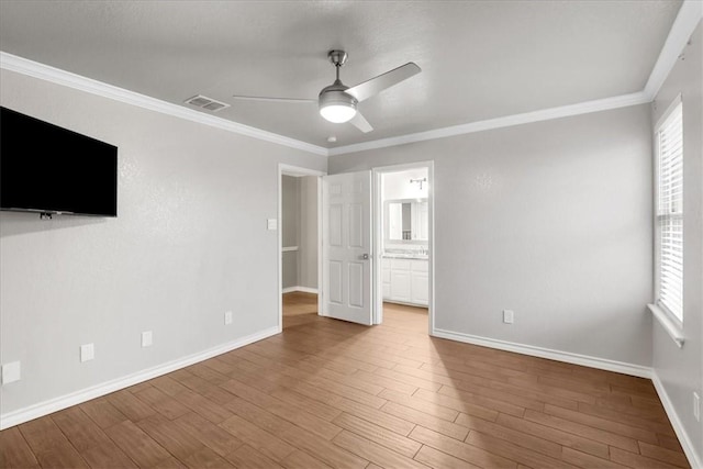 unfurnished bedroom featuring crown molding, multiple windows, visible vents, and wood finished floors