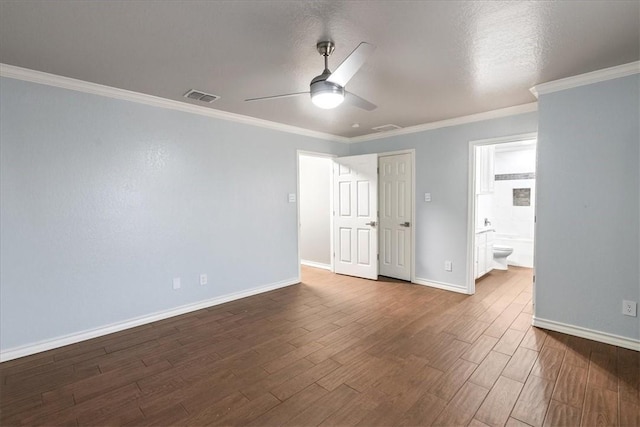 unfurnished bedroom with visible vents, baseboards, dark wood finished floors, ensuite bath, and crown molding