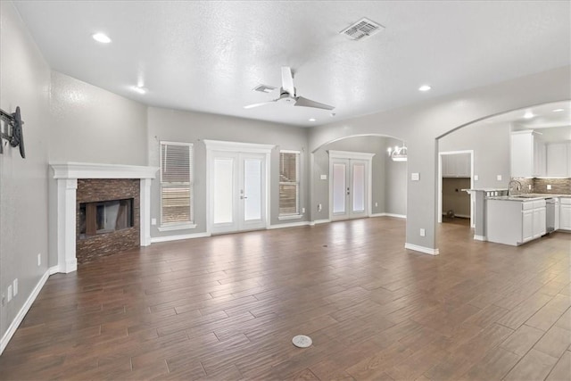 unfurnished living room featuring visible vents, a ceiling fan, dark wood-style floors, a fireplace, and recessed lighting