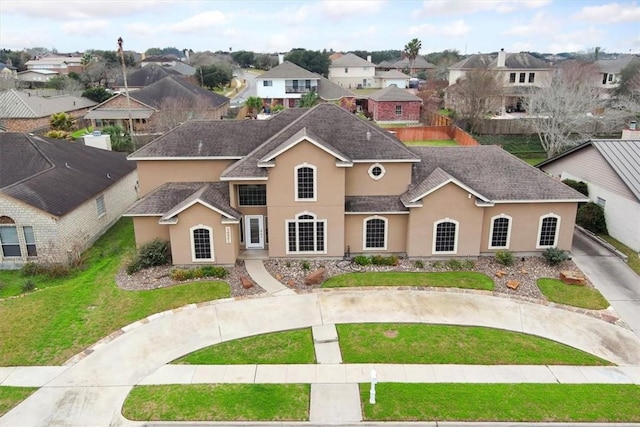 view of front facade featuring a front lawn, roof with shingles, a residential view, and stucco siding