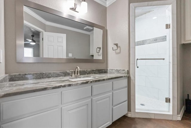 full bath with ceiling fan, a textured wall, vanity, ornamental molding, and a shower stall