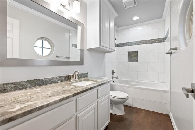 bathroom with toilet, wood finished floors, vanity, ornamental molding, and washtub / shower combination