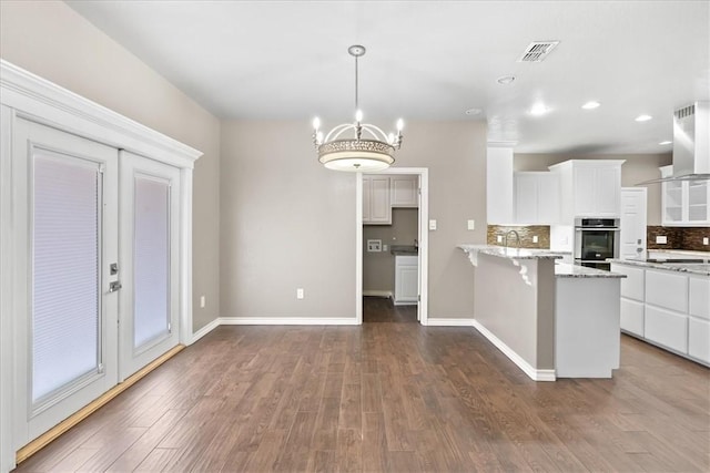 kitchen with tasteful backsplash, visible vents, dark wood-style floors, a kitchen breakfast bar, and white cabinetry