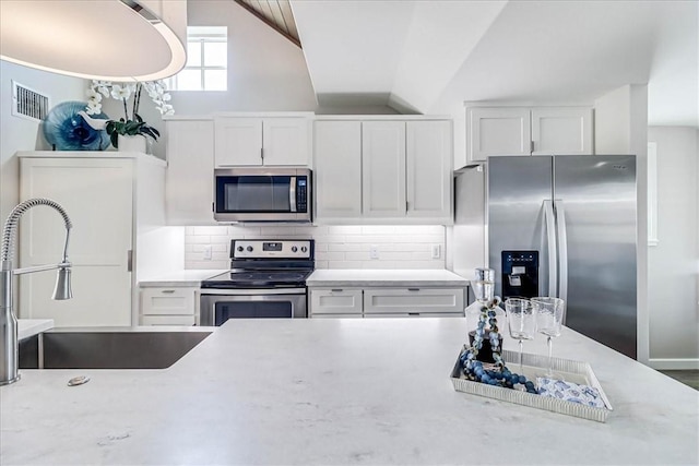 kitchen featuring white cabinetry, sink, light stone counters, decorative backsplash, and appliances with stainless steel finishes