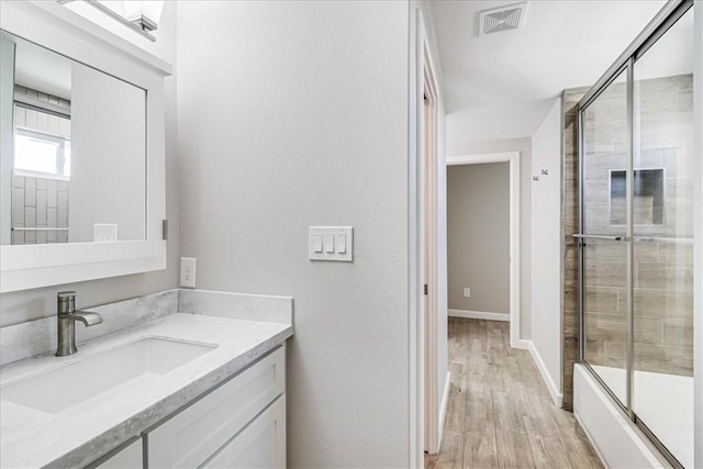 bathroom featuring hardwood / wood-style floors, vanity, and enclosed tub / shower combo