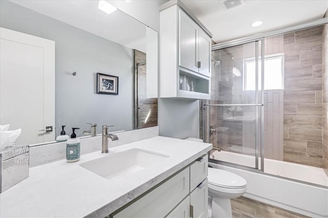 full bathroom featuring shower / bath combination with glass door, wood-type flooring, vanity, and toilet