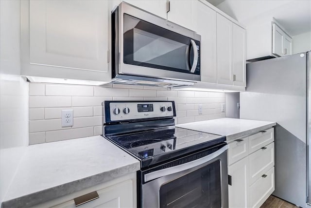 kitchen with wood-type flooring, backsplash, stainless steel appliances, and white cabinetry