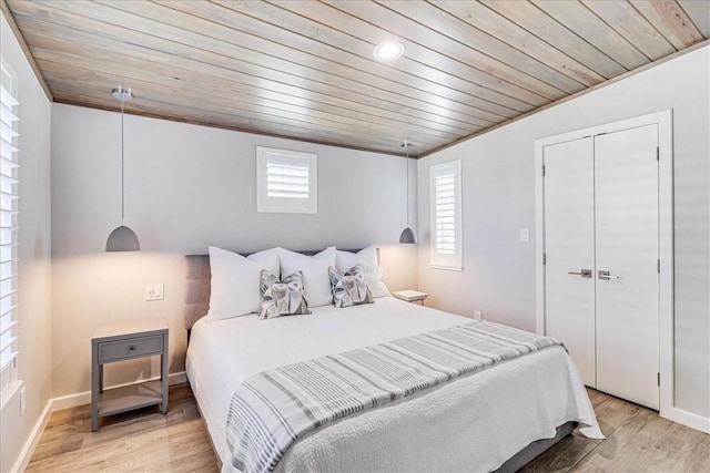 bedroom with multiple windows, a closet, wooden ceiling, and light hardwood / wood-style flooring