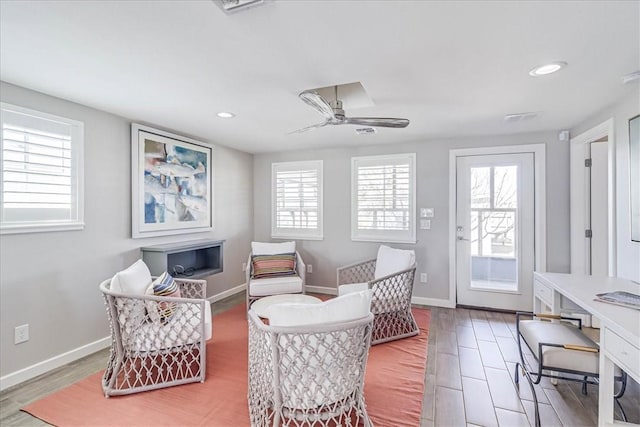 living area with hardwood / wood-style floors, ceiling fan, and plenty of natural light