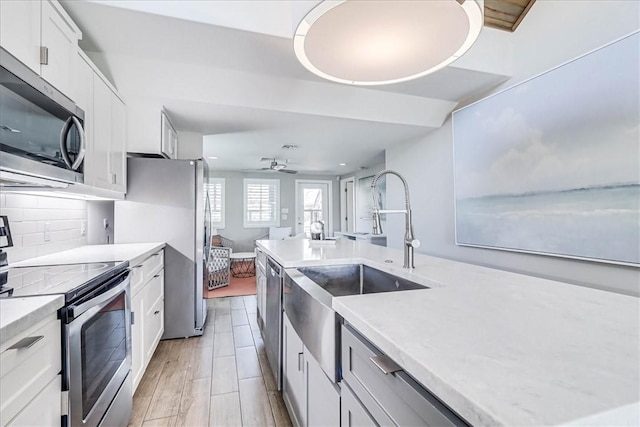 kitchen featuring backsplash, sink, ceiling fan, appliances with stainless steel finishes, and white cabinetry