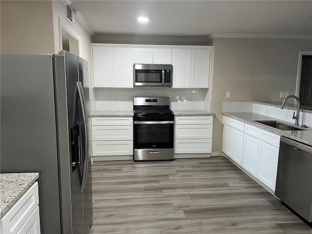 306 Circle Dr, Corpus Christi, TX 78412 - kitchen with appliances with stainless steel finishes, a sink, crown molding, white cabinetry, and light stone countertops