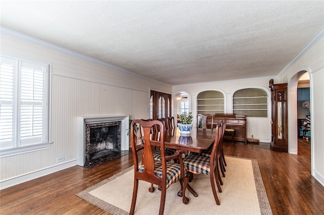 dining area with a high end fireplace, a textured ceiling, dark hardwood / wood-style flooring, and ornamental molding