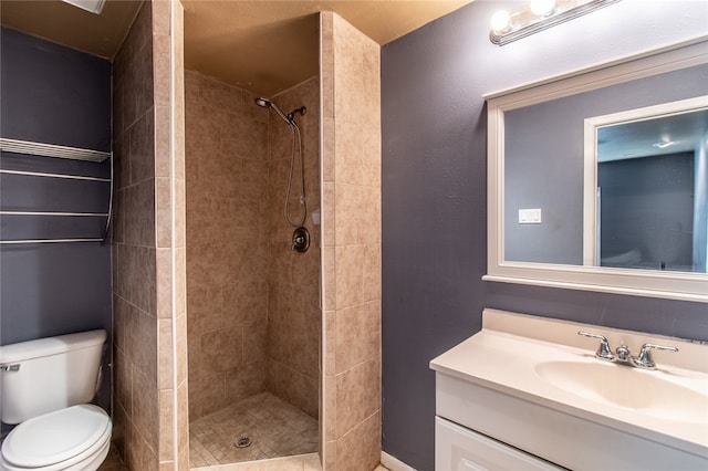 bathroom with tiled shower, toilet, and vanity