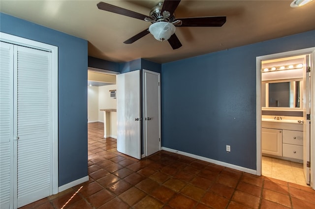 unfurnished bedroom featuring a closet, dark tile patterned floors, ceiling fan, and connected bathroom