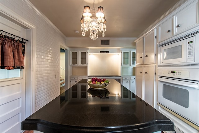 kitchen featuring white appliances, an inviting chandelier, pendant lighting, and white cabinetry