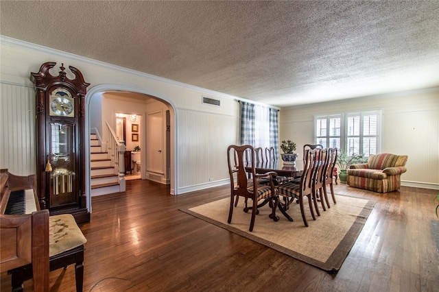 dining space with dark hardwood / wood-style floors, a textured ceiling, and crown molding