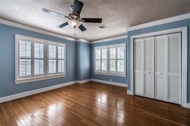 unfurnished bedroom with dark wood-type flooring, a closet, ornamental molding, and ceiling fan