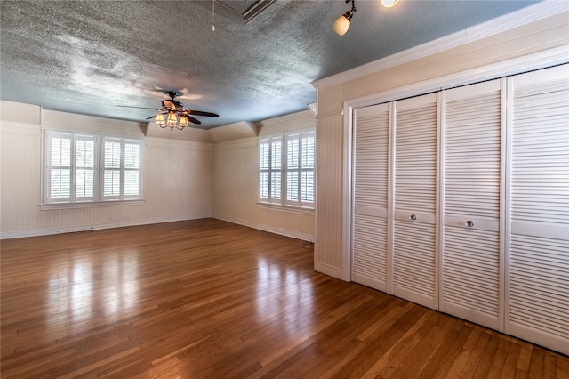 unfurnished bedroom featuring a textured ceiling, hardwood / wood-style floors, and multiple windows