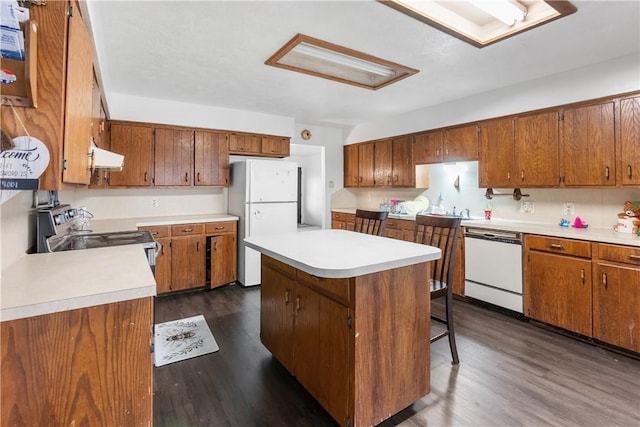 kitchen featuring ventilation hood, white appliances, dark hardwood / wood-style flooring, a kitchen island, and a breakfast bar