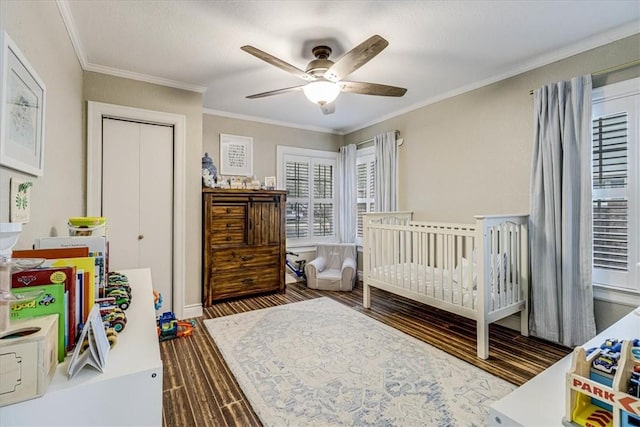 bedroom featuring ornamental molding, a nursery area, dark wood-type flooring, and ceiling fan