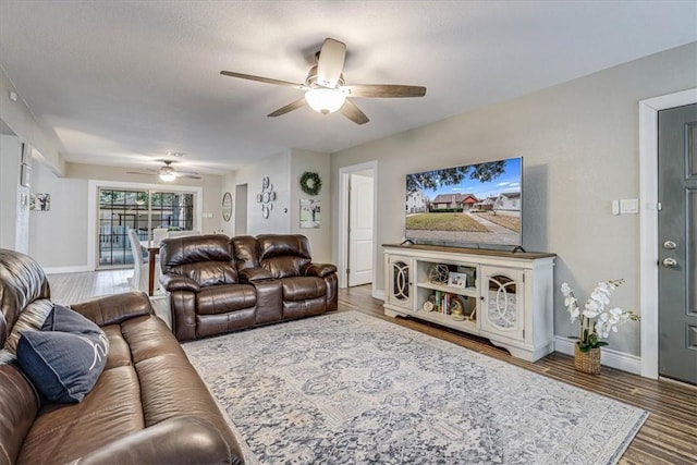 living room with ceiling fan, dark hardwood / wood-style flooring, and a textured ceiling