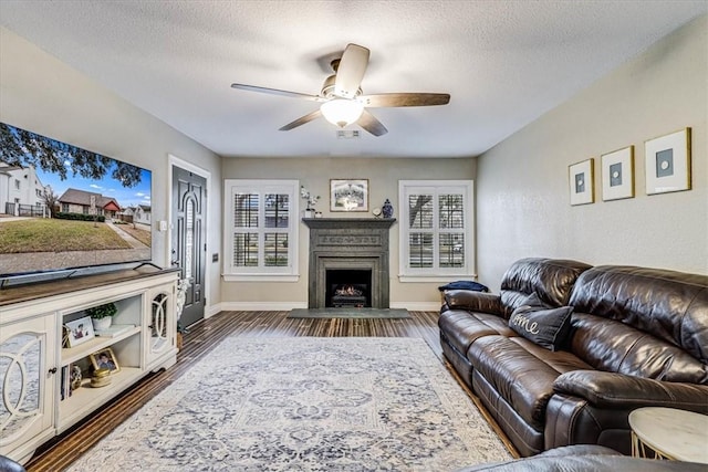 living room with dark wood-type flooring, ceiling fan, plenty of natural light, and a textured ceiling