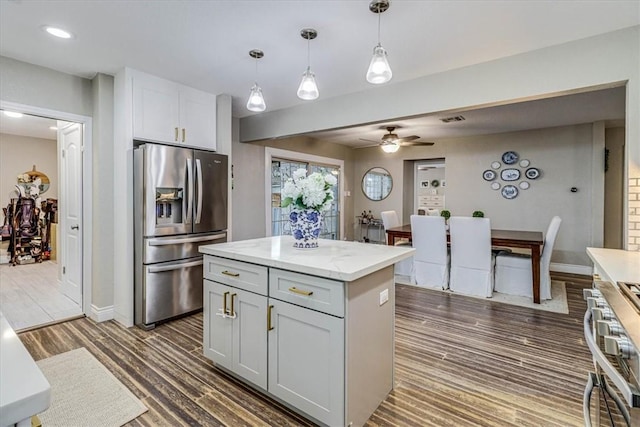 kitchen featuring dark wood-type flooring, decorative light fixtures, a kitchen island, ceiling fan, and stainless steel appliances