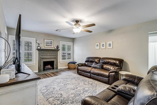 living room featuring ceiling fan, wood-type flooring, and a textured ceiling