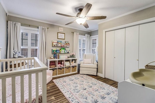 bedroom with a nursery area, ornamental molding, dark hardwood / wood-style flooring, and a closet