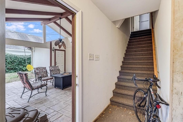 stairway featuring lofted ceiling with beams