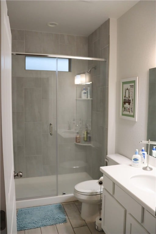 bathroom featuring tile patterned flooring, vanity, toilet, and a shower with shower door