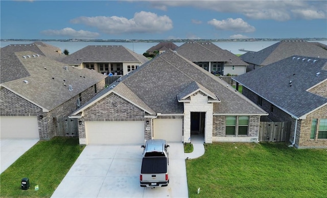 view of front of home featuring a garage, a water view, and a front lawn