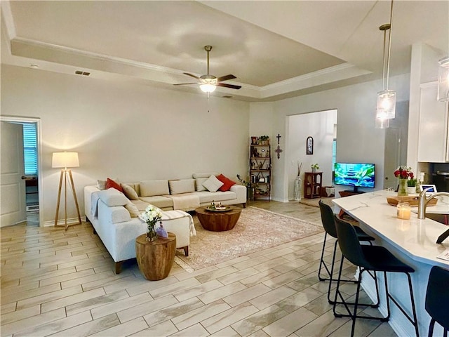 living room featuring a tray ceiling, light hardwood / wood-style flooring, and ceiling fan