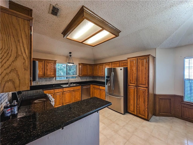 14929 Red River Dr, Corpus Christi, TX 78410 - kitchen with stainless steel appliances, healthy amount of natural light, brown cabinetry, a wainscoted wall, and a textured ceiling