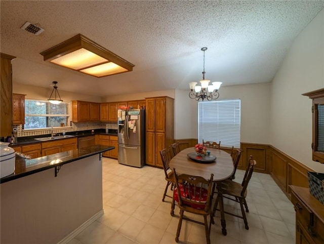 14929 Red River Dr, Corpus Christi, TX 78410 - kitchen with stainless steel refrigerator with ice dispenser, a sink, brown cabinets, dark countertops, and a chandelier