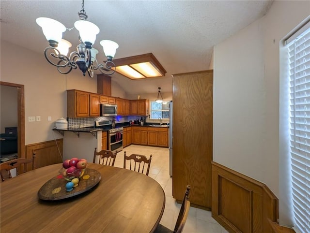 14929 Red River Dr, Corpus Christi, TX 78410 - dining area featuring light tile patterned floors, wainscoting, a chandelier, and a textured ceiling