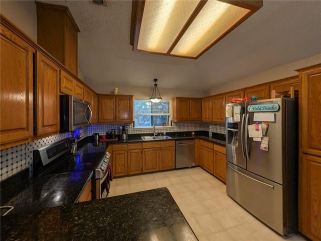 14929 Red River Dr, Corpus Christi, TX 78410 - kitchen featuring stainless steel appliances, a sink, brown cabinetry, tasteful backsplash, and dark stone counters