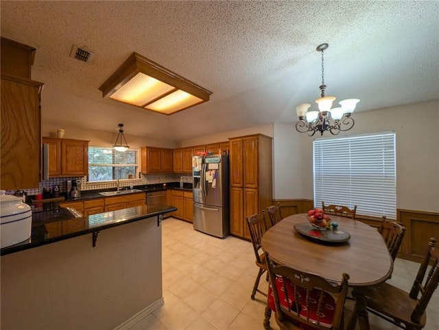 14929 Red River Dr, Corpus Christi, TX 78410 - kitchen with stainless steel fridge with ice dispenser, a sink, brown cabinetry, a peninsula, and wainscoting