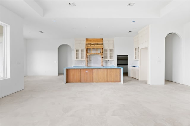 758 Buffalo Creek Dr, Corpus Christi, TX 78415 - kitchen featuring arched walkways, glass insert cabinets, white cabinets, a center island, and open floor plan