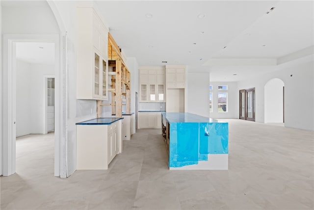 758 Buffalo Creek Dr, Corpus Christi, TX 78415 - kitchen featuring arched walkways, glass insert cabinets, a center island, white cabinetry, and dark countertops