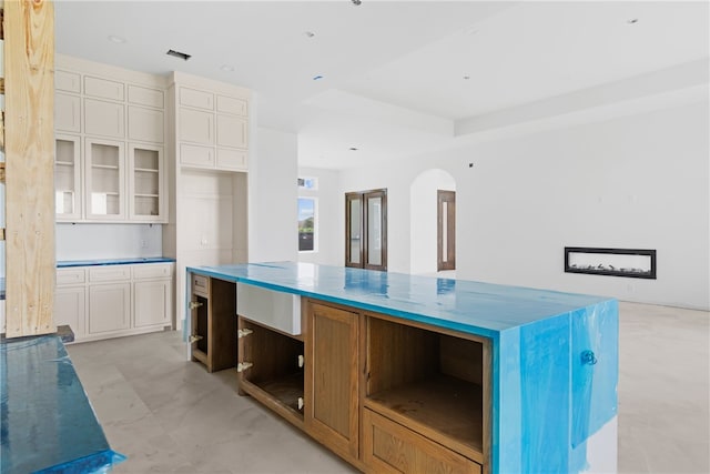 758 Buffalo Creek Dr, Corpus Christi, TX 78415 - kitchen featuring open shelves, arched walkways, white cabinetry, glass insert cabinets, and a kitchen island