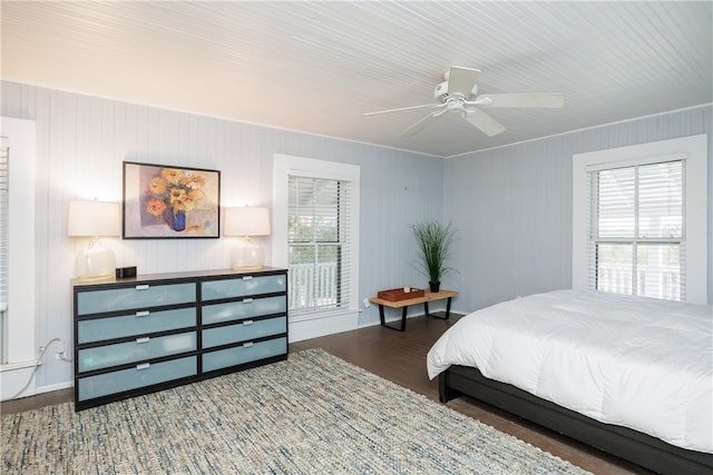 bedroom with dark wood-type flooring, wooden walls, and ceiling fan