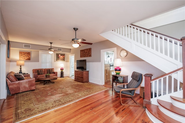 living room with wood walls, hardwood / wood-style flooring, and ceiling fan