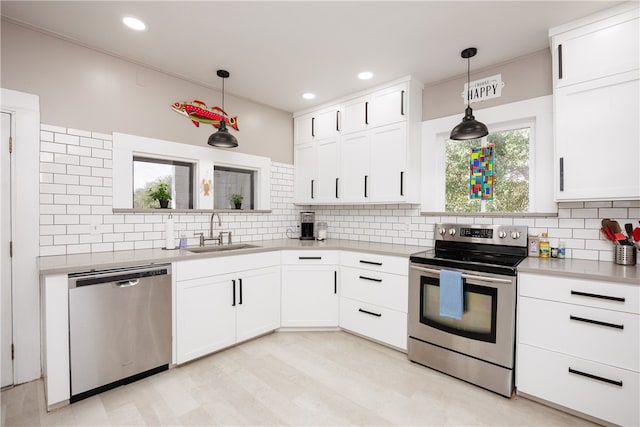 kitchen featuring white cabinetry, appliances with stainless steel finishes, decorative light fixtures, backsplash, and sink