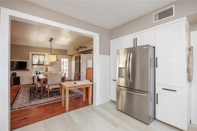 kitchen featuring white cabinets, light wood-type flooring, pendant lighting, and stainless steel fridge with ice dispenser