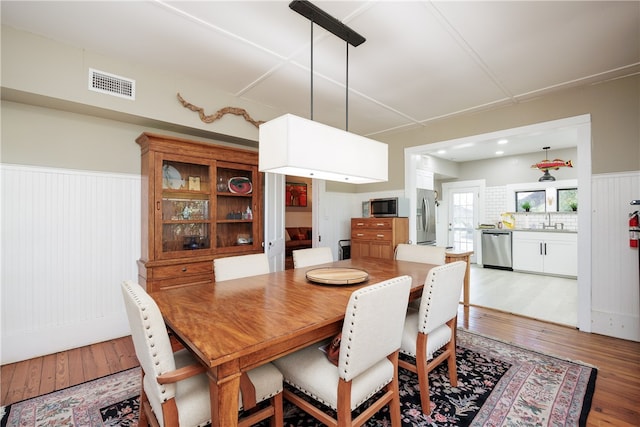 dining area featuring hardwood / wood-style flooring, wooden walls, and sink