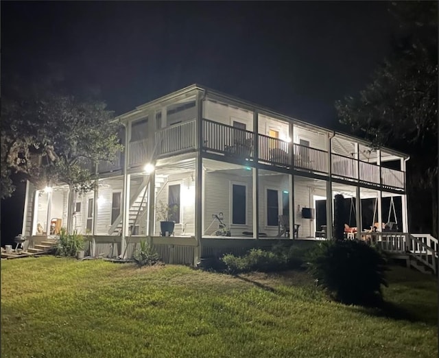 back of house at twilight with a yard and a balcony